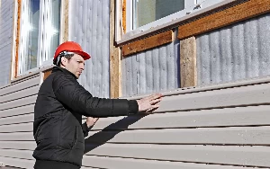 Triangle Painting employee repairing house siding